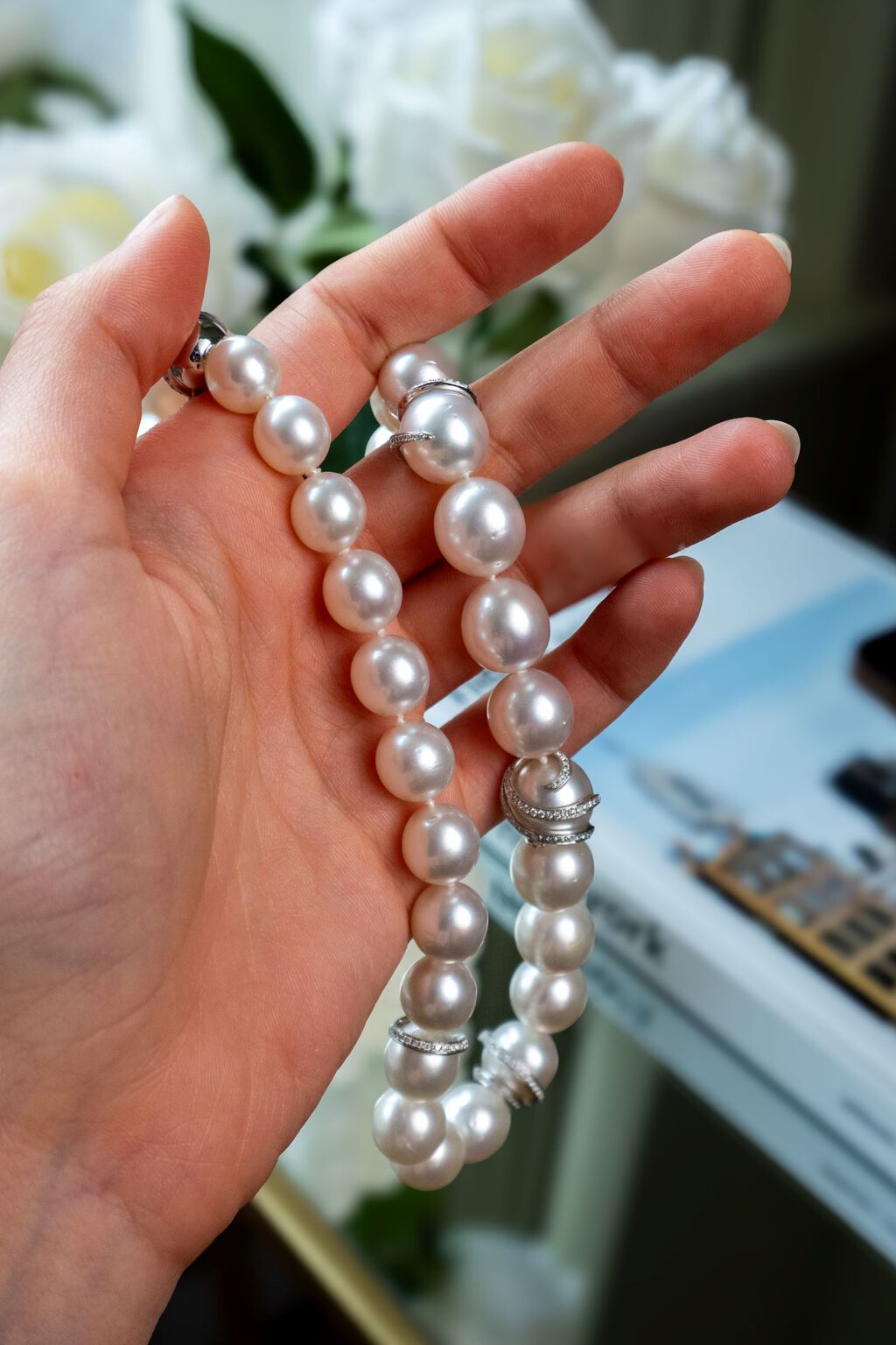 Woman's hand holding cream colored South SEa pearls. 